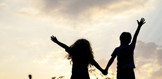 Silhouette, group of happy children playing on meadow, sunset, s